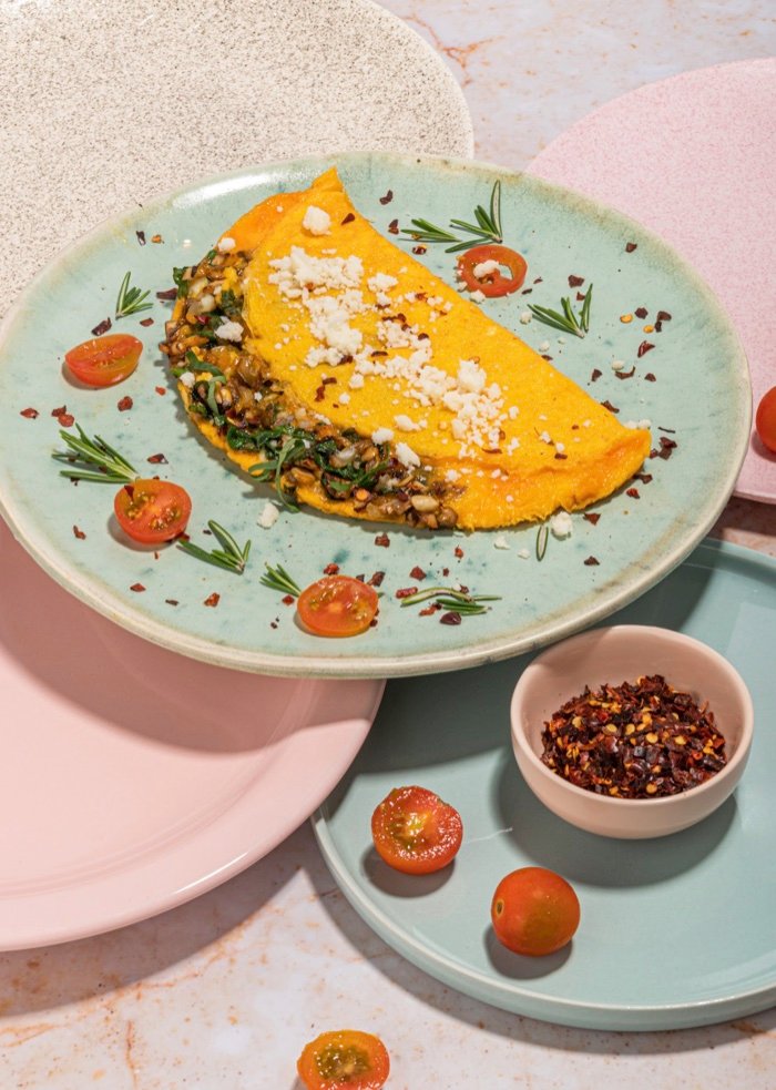 Omelette con vegetales y queso sobre un plato verde